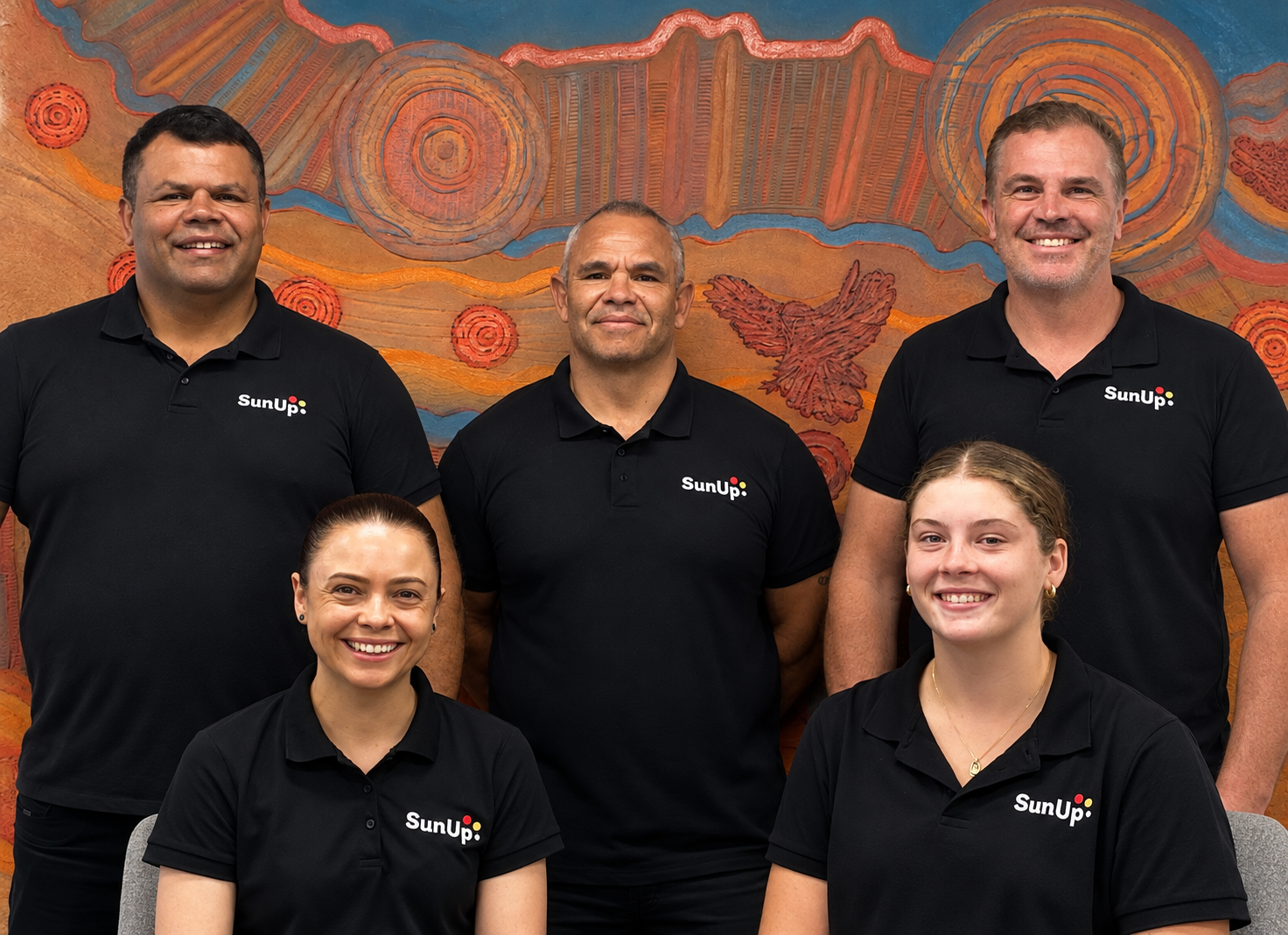 Five members of the SunUp team in branded polos, pictured together in front of Aboriginal artwork
